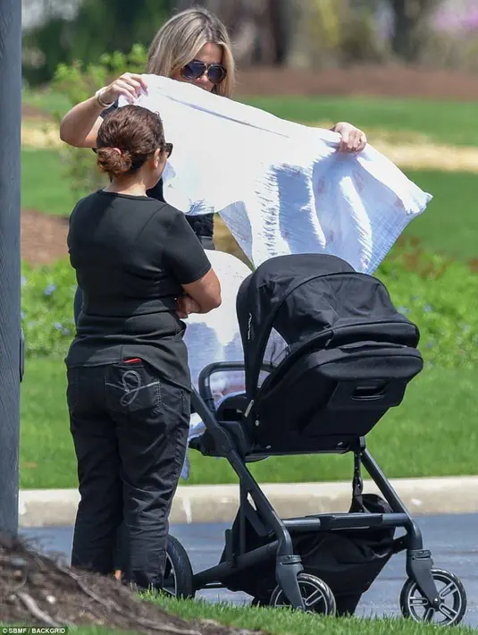 Khloe Kardashian dibantu oleh seorang asisten saat mengajak True jalan-jalan. (SBMF/BACKGRID/DailyMail)