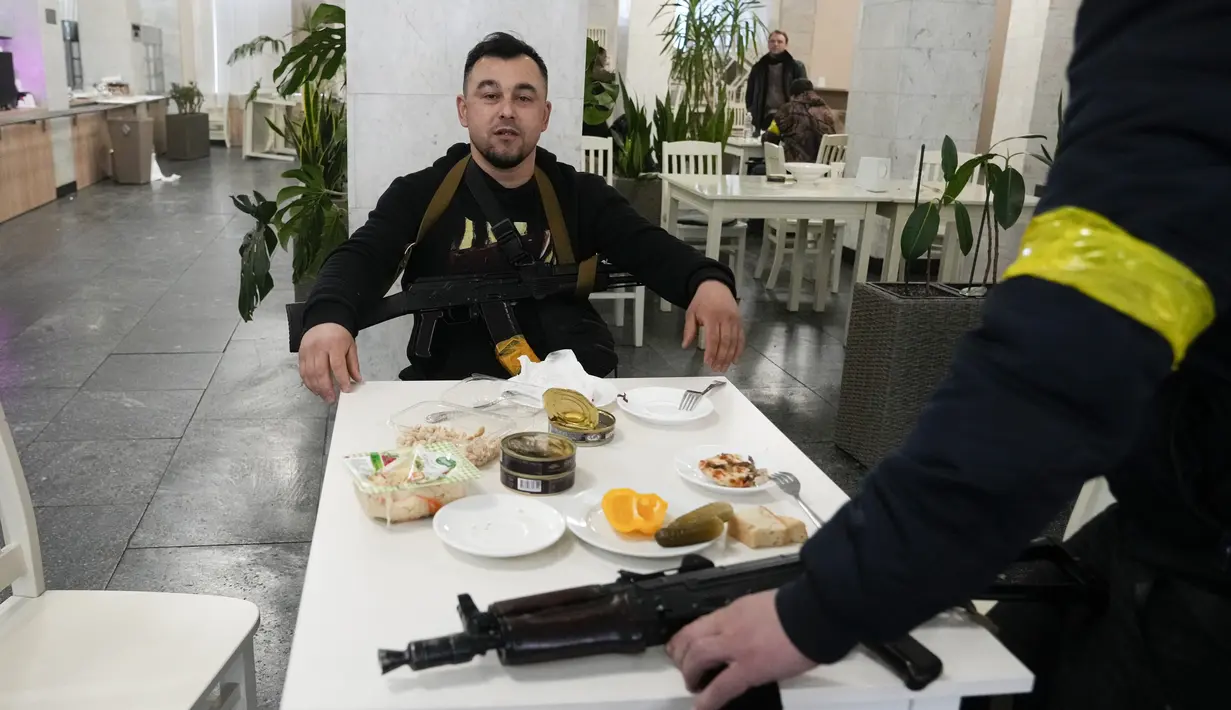 Anggota pertahanan sipil makan saat jeda tugas mereka di Balai Kota di Kiev, Ukraina, Minggu (27/2/2022). Pihak berwenang Ukraina mengatakan bahwa pasukan Rusia telah memasuki kota terbesar kedua di Ukraina Kharkiv dan pertempuran di jalan-jalan. (AP Photo/Efrem Lukatsky)