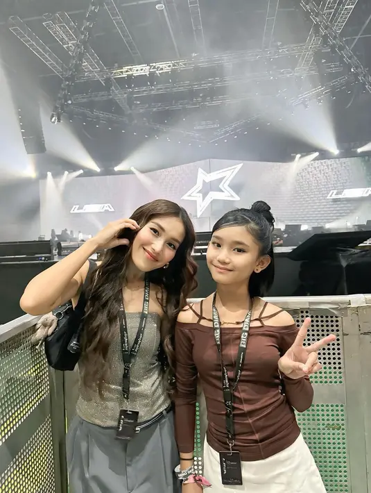 Ia tampil anggun dengan busana sederhana namun tetap modis. Ayu mengenakan tube top silver berkilau , dipadukan dengan mini skirt abu-abu kaus kaki abu-abu panjang dan sepatu loafers hitam beraksen glossy. Penampilannya terlihat santai, tetapi tetap elegan, menunjukkan sisi modern seorang ibu sekaligus penggemar. [@ayutingting92].