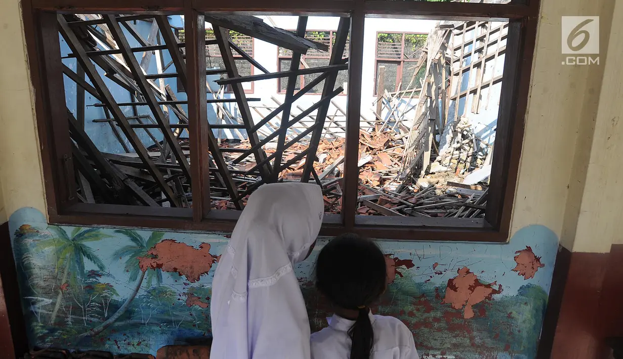 Dua orang siswi melihat bangunan kelas yang ambruk di SD Negeri Kotabatu 08 Kecamatan Ciomas Kabupaten Bogor, Senin (23/7). Ambruknya dua bangunan kelas mengakibatkan terganggunya proses kegiatan belajar mengajar. (Merdeka.com/Arie Basuki)