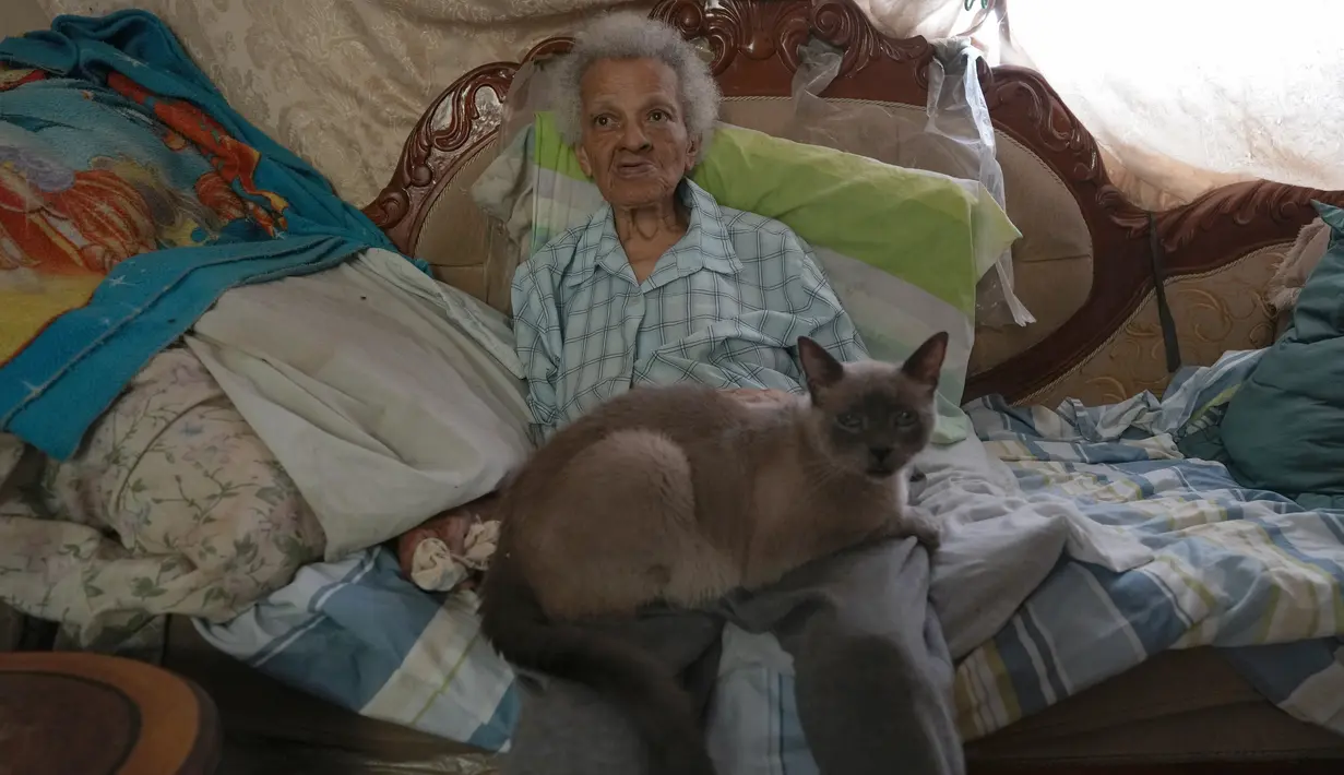 Zenobia Ansualve duduk di ruang tamu bersama kucingnya Cenizo, di Caracas, Venezuela, pada 18 Agustus 2021. Ansualve (88) yang tinggal sendiri dan tidak meninggalkan rumahnya sejak awal pandemi COVID-19, mengatakan hidup dengan $20 sebulan dari menyewakan kamar miliknya. (AP Photo/Ariana Cubillos)