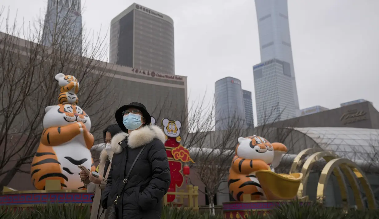Wanita berjalan dekat hiasan harimau yang dipajang di Kawasan Pusat Bisnis Beijing, Minggu (9/1/2022). Tianjin memulai pengujian massal terhadap 14 juta penduduknya setelah sekelompok anak-anak dan orang dewasa dinyatakan positif COVID-19, beberapa dengan varian omicron. (AP Photo/Andy Wong)