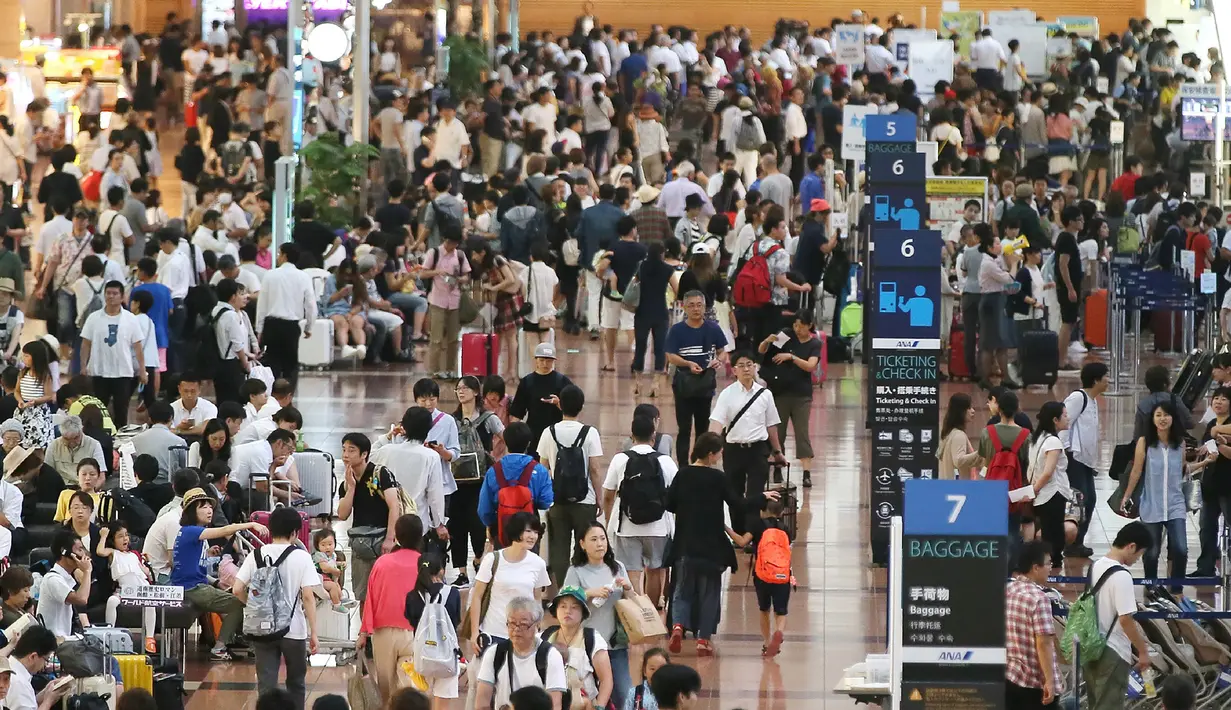 Puluhan calon penumpang berkerumun di lobi keberangkatan Bandara Haneda di Tokyo, Senin (22/8). Topan Mindulle yang bergerak menuju Tokyo menyebabkan hampir 400 penerbangan dibatalkan akibat hujan lebat dan angin kencang. (Jiji Press/AFP)