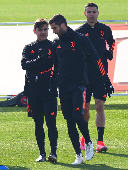 Penyerang Juventus, Paulo Dybala berbincang dengan gelandang Rodrigo Bentancur saat sesi latihan tim di tempat latihan Juventus di Turin, Italia (16/2/2021).  Juventus akan bertanding ke markas Porto pada leg pertama babak 16 besar Liga Champions di Estadio do Dragao. (AFP/Marco Bertorrello)