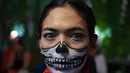 Seorang wanita melukis wajahnya saat pesta Halloween di sebuah kafe di Tangerang (31/10/2021). (AFP/Adek Berry)