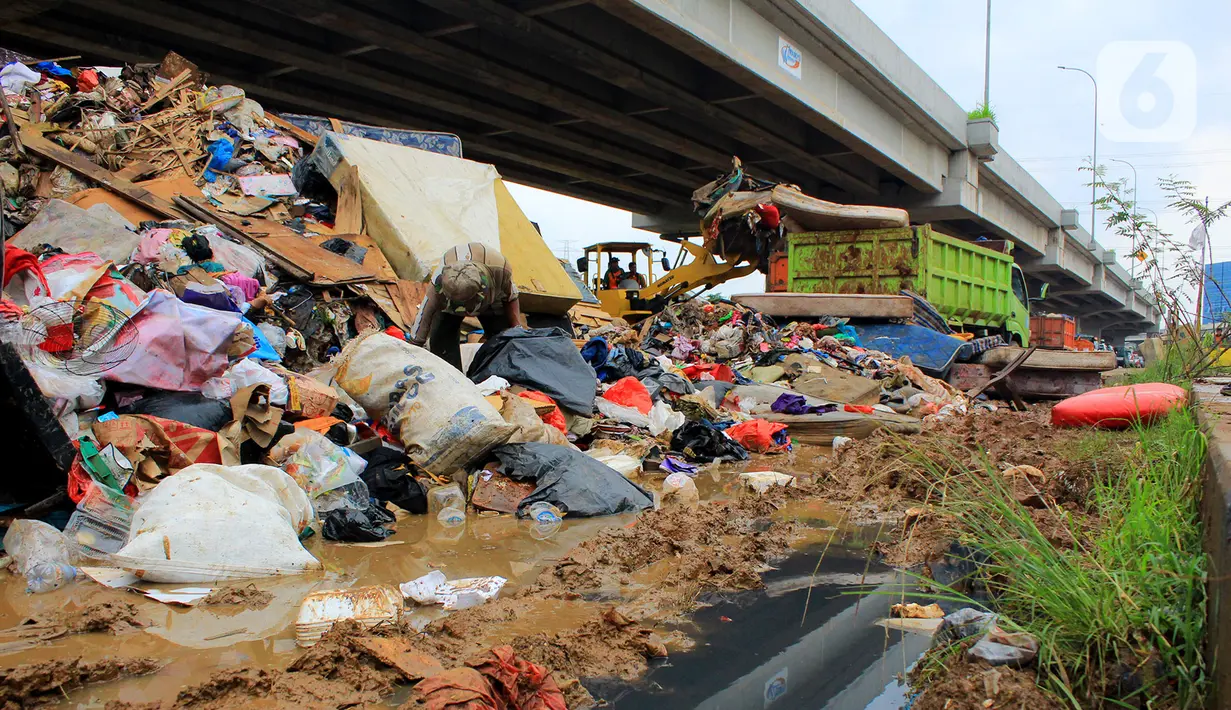 Petugas PPSU DKI Jakarta menggunakan alat berat saat mengangkut sampah sisa banjir di bawah Tol Becakayu, Cipinang Melayu, Jakarta Timur, Rabu (8/1/2020). Sampah sisa banjir tersebut selanjutnya diangkut ke TPA Bantar Gebang. (merdeka.com/Magang/Muhammad Fayyadh)