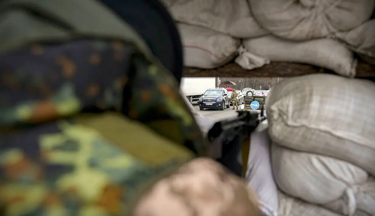 Seorang prajurit Ukraina memantau sebuah pos pemeriksaan dari balik karung pasir di jalan utama di Kyiv, Ukraina, 7 Maret 2022. PBB tidak dapat memenuhi kebutuhan jutaan warga sipil yang terjebak dalam konflik di Ukraina. (AP Photo/Vadim Ghirda)