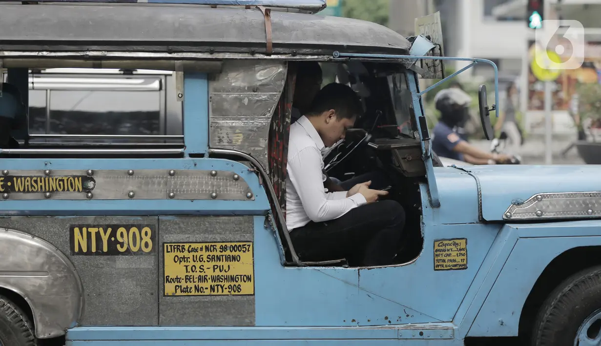 Pengemudi mobil Jeepney bermain handphone saat berada di Manila, Filipina, Jumat (22/11/2019). Jeepney merupakan transportasi umum paling populer dan sudah menjadi ikon di Filipina. (Bola.com/M Iqbal Ichsan)