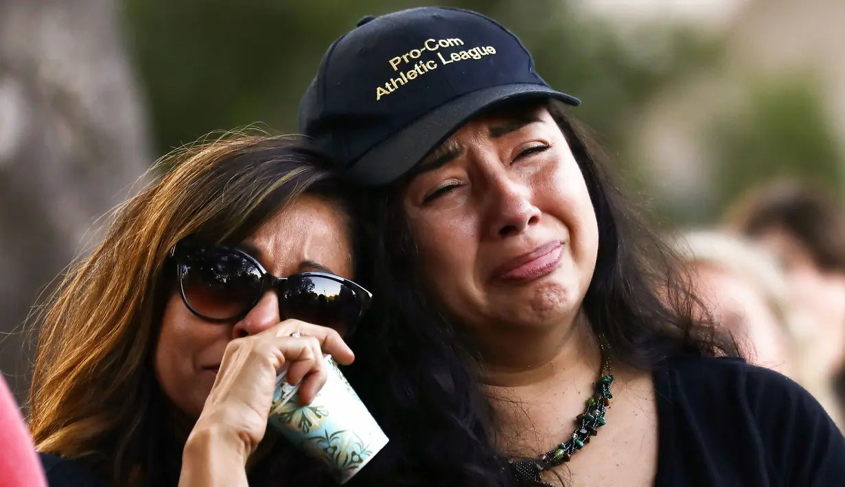 Dua wanita menangis saat menghadiri acara untuk korban penembakan brutal di festival kuliner Gilroy Garlic di Gilroy, California (29/7/2019). Tiga orang tewas dan sedikitnya puluhan orang terluka akibat kejadian tersebut. (AFP Photo/Mario Tama)