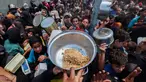 Warga Palestina berkumpul untuk menerima makanan hangat di titik distribusi makanan di kamp Nuseirat, Jalur Gaza Tengah pada 21 Mei 2025. (Eyad BABA/AFP)