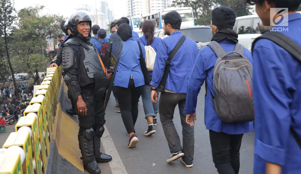 Personel Brimob memberikan senyum kepada rombongan mahasiswa yang akan kembali usai berunjuk rasa di sekitar Jembatan Layang Gerbang Pemuda, Jakarta, Selasa (1/10/2019). Mahasiswa dari berbagai perguruan tinggi kembali berunjuk rasa menolak beberapa RUU. (Liputan6.com/Helmi Fithriansyah)