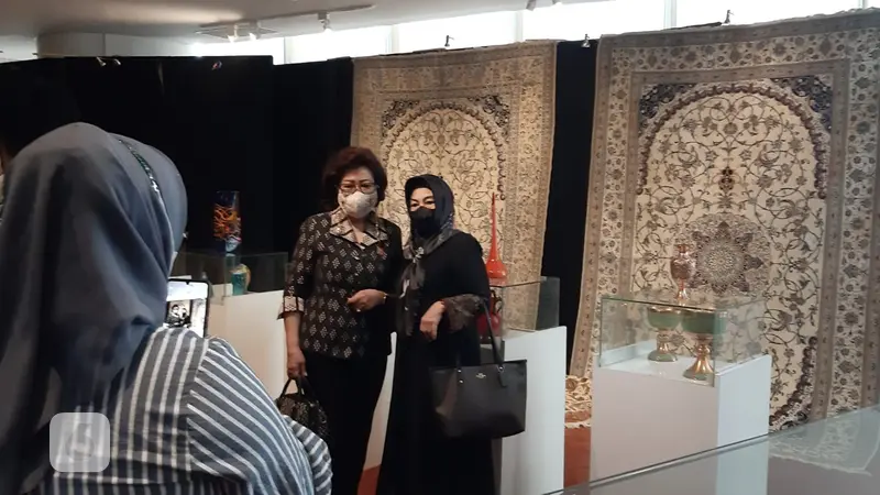 Pengunjung mengambil foto dengan latar karpet Iran di Perpusnas.