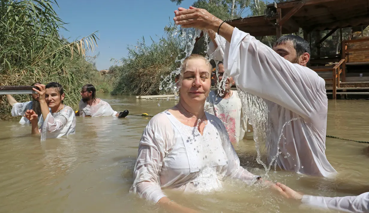 Pendeta membaptis umat Kristen di Qasr al-Yahud, Sungai Yordan, Jericho, Palestina, Jumat (13/9/2019). Area ini dulu adalah kawasan perang antara Israel dengan negara-negara Arab. (HAZEM BADER/AFP)