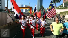 Sejumlah remaja membawa bendera negara-negara peserta Sea Games di Jakarta, Minggu (30/4). Kirab itu berlangsung guna menyambut Sea Games Kuala Lumpur 2017. (Liputan6.com/Johan Tallo)