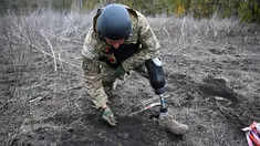 Andriy Ilkiv, seorang penjinak ranjau dari kepolisian nasional Ukraina, yang kehilangan kakinya tahun lalu akibat ledakan ranjau, mencari ranjau di sebuah ladang di distrik Izyum, wilayah Kharkiv, di tengah invasi Rusia ke Ukraina pada 24 Oktober 2023. (SERGEY BOBOK / AFP)