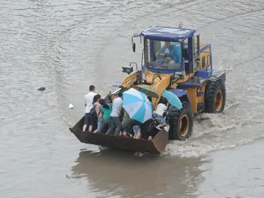 Sejumlah warga berada di ekskavator saat banjir melanda Taiyuan, Provinsi Shanxi, China, (20/7). Curah hujan terberat yang mengguyur China selama beberapa hari terakhir telah mengakibatkan banjir merendam sejumlah daerah. (REUTERS/Stringer)