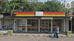 Warga berjalan di depan toko Rest Area KM 50 A yang ditutup secara permanen pada 20 Desember 2020 lalu di Tol Jakarta-Cikampek, Karawang, Kamis (24/12/2020). PT Jasa Marga menjelaskan alasan penutupan yang memang sudah direncanakan ditutup sejak Februari lalu. (Liputan6.com/Herman Zakharia)