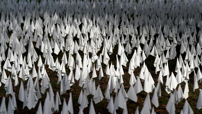 Matahari bersinar di atas bendera putih yang ditanam untuk mengenang warga Amerika yang meninggal karena COVID-19 di dekat Stadion RFK di Washington, Selasa (27/10/2020). Instalasi seni Suzanne Brennan Firstenberg itu disebut 