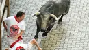 Dua orang peserta berusaha menghindar dari serudukan banteng  selama hari ketiga Festival San Fermin di Pamplona, Spanyol utara, (9/7). (AFP Photo/Jose Jordan)