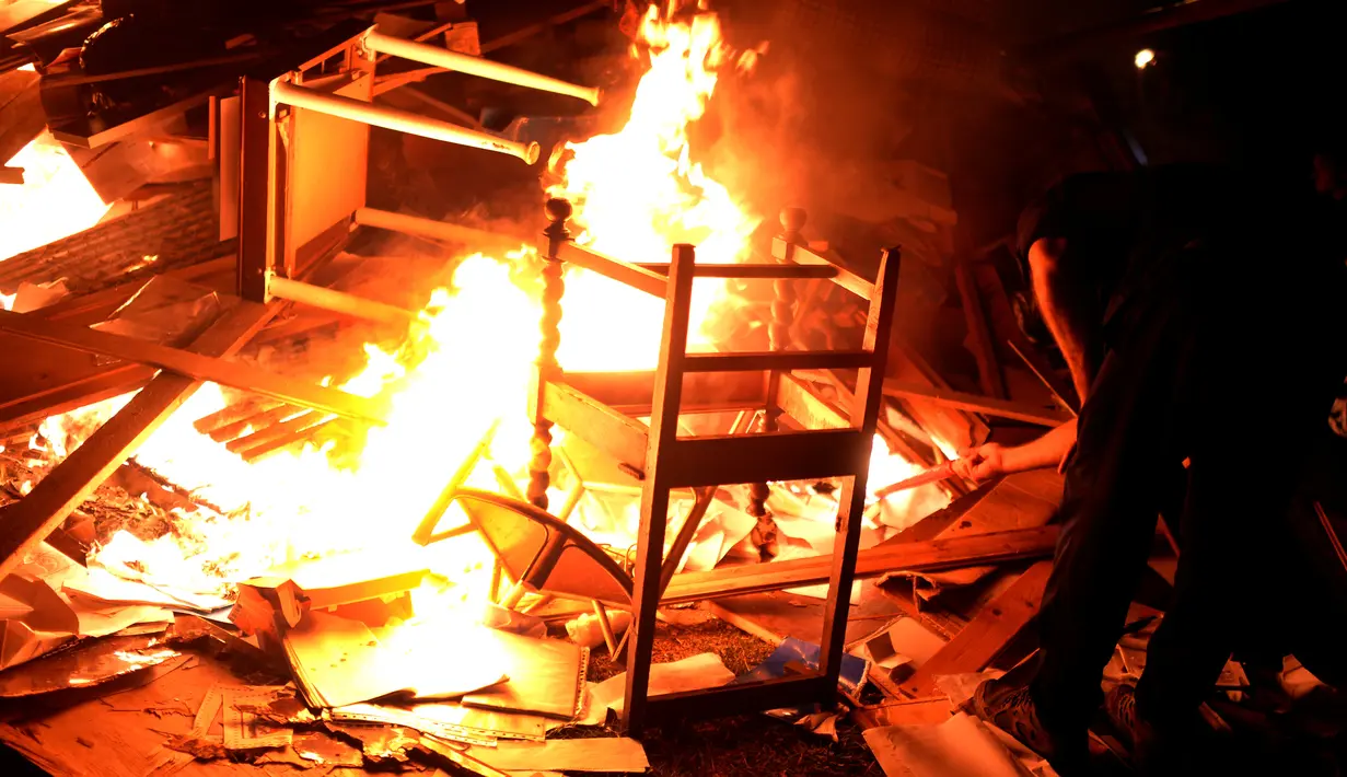 Seorang warga membakar barang-barang yang tidak diinginkan saat mengikuti tradisi malam San Juan's (Saint John) di Gijon, Spanyol, (24/6/). Malam San Juan juga dilakukan dengan berenang saat musim panas tiba. (REUTERS/Vincent West)