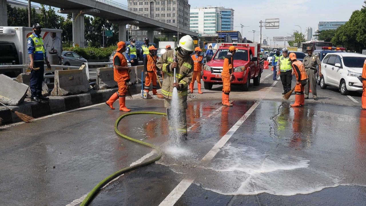 Petugas berseragam oranye melakukan pembersihan sisa-sisa material kecelakaan mobil dump truk  di Jalan Gatot Subroto, Jakarta, Selasa (9/1/2024).