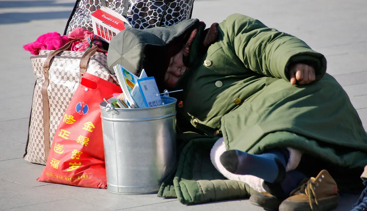 Seorang wanita tidur di dekat barang bawaannya saat menunggu keberangkatan kereta yang akan ditumpanginya di Stasiun Beijing, Selasa (2/2). Warga China sedang mempersiapkan menyambut Tahun Baru Imlek yang jatuh pada 8 Februari (Reuters/Kim Kyung-Hoon)