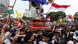 Seorang peserta menaiki Ogoh-ogoh membawa bendera merah putih saat aksi Kita Indonesia di kawasan Bundaran HI, Jakarta, Minggu (04/12). Aksi tersebut adalah acara perayaan kegembiraan atas keberagaman dan kebangsaan Indonesia. (Liputan6.com/Fery Pradolo)