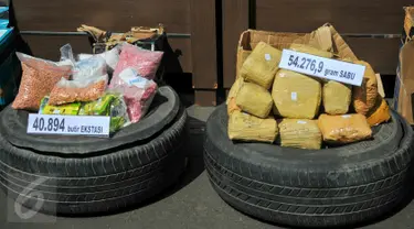 Petugas memperlihatkan barang bukti sabu dan pil ekstasi yang berhasil diamankan oleh BNN, Jakarta, Jumat (13/5). 54 kg sabu dan 40 ribu butir pil ekstasi yang disita dari jaringan internasional itu disimpan di ban serep mobil. (Liputan6.com/Yoppy Renato)