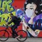 Pengendara sepeda melewati grafiti bertema virus corona COVID-19 yang bertuliskan ‘Happy Easter’ pada dinding di Hamm, Jerman, Senin (13/4/2020). Kasus COVID-19 tertinggi di dunia ditempati oleh Amerika Serikat, Spanyol, Italia, Prancis, Jerman, dan China. (AP Photo/Martin Meissner)