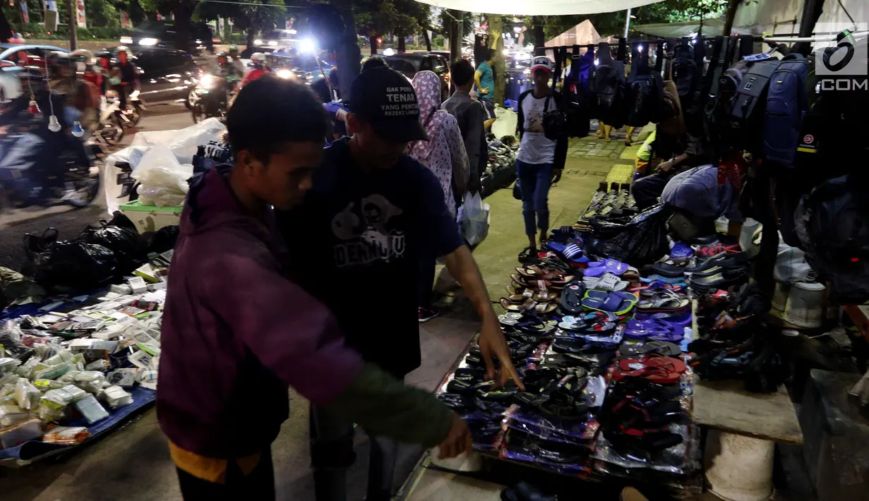 Calon pembeli melihat dagangan PKL di trotoar Jalan Sudirman di Kawasan Bendungan Hilir, Jakarta Pusat, Selasa (30/1). Sejak beberapa bulan terakhir, puluhan PKL menggelar lapaknya di trotoar jalan protokol Ibu Kota tersebut. (Liputan6.com/JohanTallo)