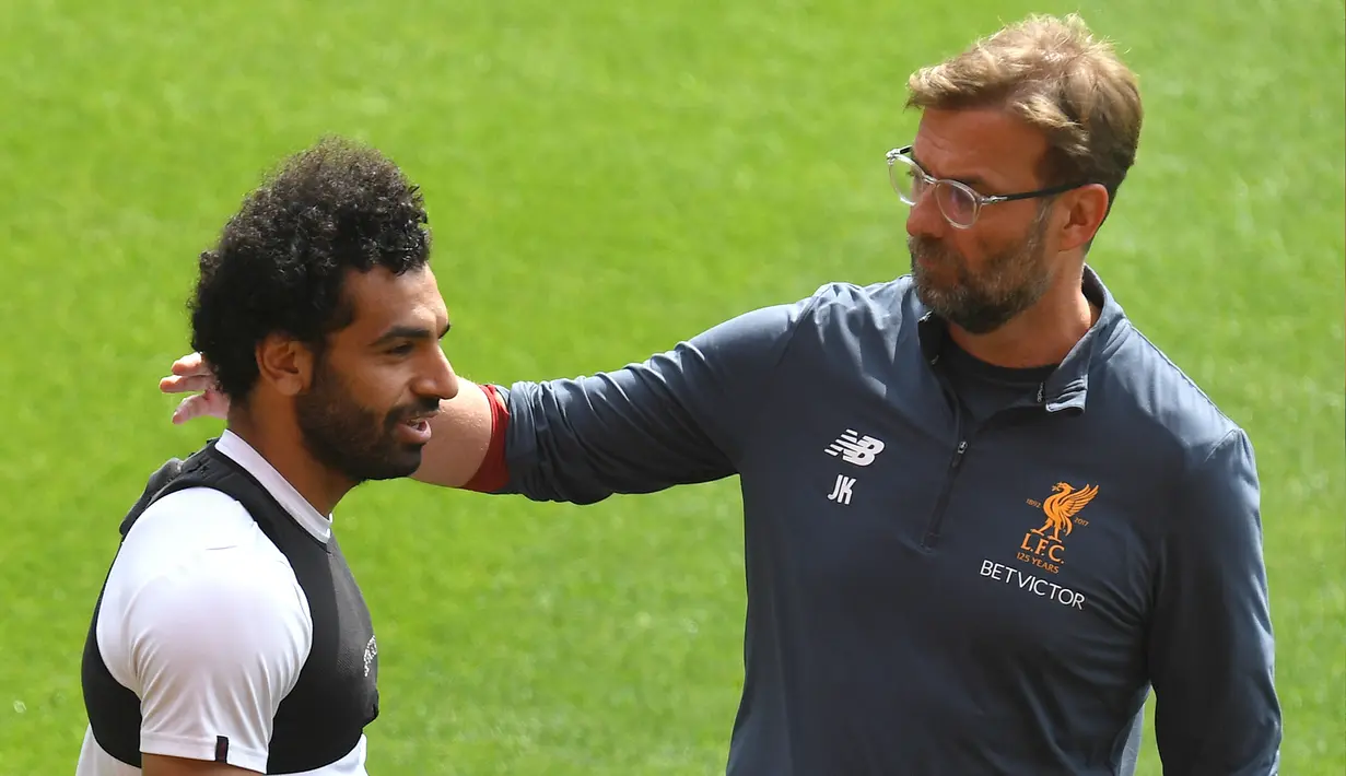 Gelandang Liverpool, Mohamed Salah berbincang dengan pelatih Jurgen Kloop saat latihan di stadion Anfield, Inggris (21/5). Pemain 25 tahun asal Mesir ini merupakan pencetak gol terbanyak tim pada musim ini. (AFP Photo/Paul Ellis)