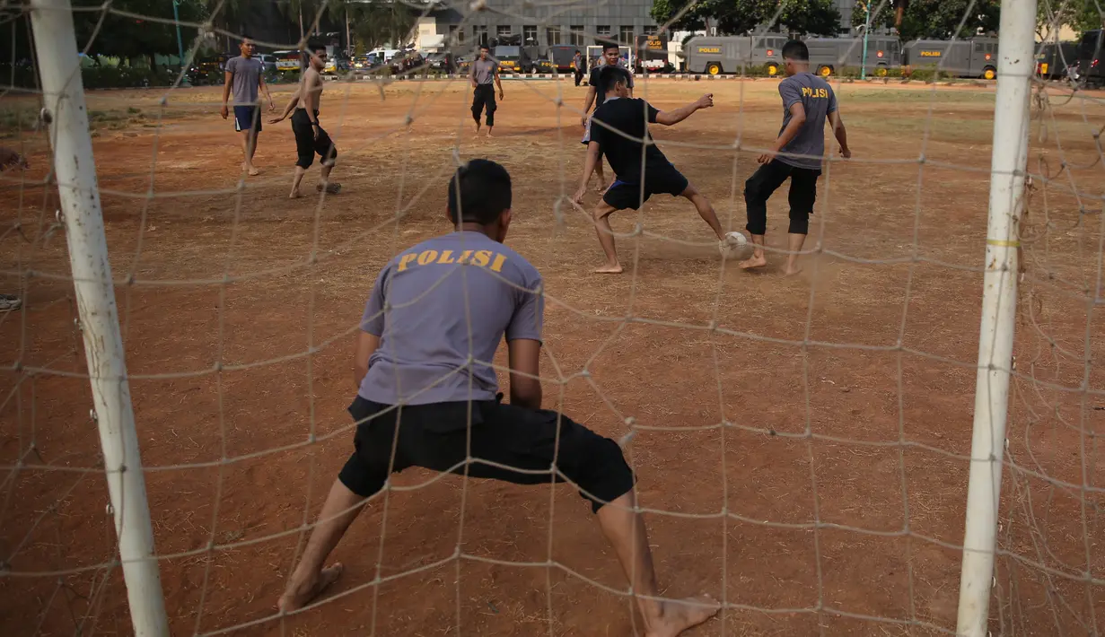 Polisi dari kesatuan Sabhara merenggangkan otot dengan bermain bola di Kawasan Polda Metro, Jakarta, Selasa (13/10/2015). Pihak Kepolisian dan TNI bersiap siaga menjelang laga Final Piala Presiden 2015. (Bola.com/Nicklas Hanoatubun).