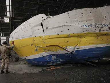 Prajurit Ukraina menyentuh hidung pesawat Antonov An-225 Mriya di bandara Antonov di Hostomel, 2 April 2022. Di pintu masuk Bandara Antonov, pasukan menjaga posisinya, tanda mereka memegang kendali penuh atas landasan pacu yang coba diserbu Rusia di hari-hari pertama perang. (AP Photo/Vadim Ghirda)