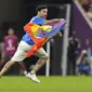 Seorang pria membawa bendera pelangi yang identik dengan LGBT berlari melintasi lapangan selama pertandingan grup H Piala Dunia 2022 Qatar antara Portugal melawan Uruguay di Stadion Lusail di Lusail, Qatar, Senin, 28 November 2022.  Pria itu berada di lapangan selama sekitar 30 detik, sebelum akhirnya dikawal oleh petugas keamanan. (AP Photo/Themba Hadebe)