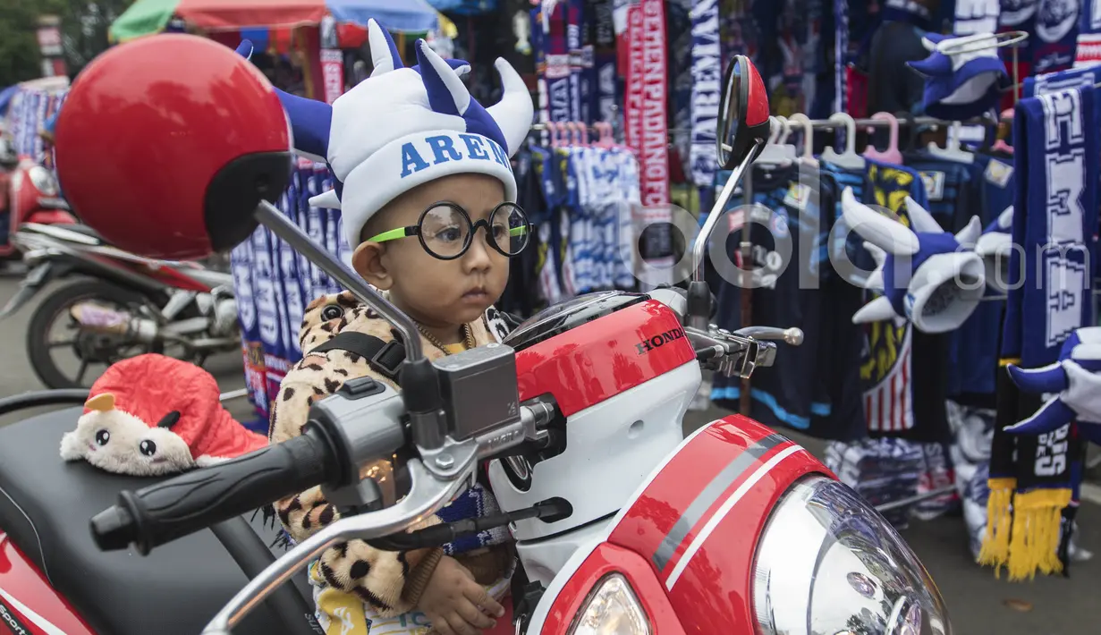 Seorang anak mengunakan atribut Arema FC yang dibeli dari pedagang kaki lima jelang laga semifinal Piala Presiden 2017 antara Arema FC melawan Semen Padang di sekitar Stadion Kanjuruhan, Malang, Jawa Timur, Minggu (5/3/2017). (Bola.com/Vitalis Yogi Trisna