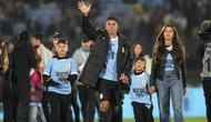 Pemain Uruguay, Luis Suarez (tengah) bersama ketiga anaknya melambaikan tangan kepada para penonton saat acara perpisahannya dengan Timnas Uruguay sebelum laga kualifikasi Piala Dunia 2026 melawan Paraguay yang berlangsung di Stadion Centenario, Montevideo, Uruguay, Sabtu (07/09/2024) WIB. (AFP/Dante Fernandez)