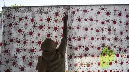 Penyandang disabilitas menjemur kain batik dengan motif virus corona di Surabaya, Jawa Timur (19/8/2020). Di tengah pandemi Covid-19, sekelompok penyandang disabilitas di Surabaya membuat batik bermotifkan virus corona. (AFP/JUNI KRISWANTO)