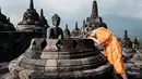 Seorang biksu Buddha berdoa di depan patung di salah satu stupa Candi Borobudur di Magelang, Jawa Tengah, pada 10 Mei 2025. (YASUYOSHI CHIBA/AFP)