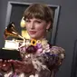 Taylor Swift berpose dengan penghargaan album tahun ini untuk "Folklore" di Grammy Awards tahunan ke-63 di Los Angeles Convention Center (14/3/2021). Album ini ditulis dan dirilis Taylor Swift sebagai sebuah proyek kejutan dan dadakan selama pandemi berlangsung. (AP Photo/Jordan Strauss)