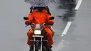 Pengendara sepeda motor menggunakan payung berkendara di sepanjang jalan di bawah hujan lebat di Chennai ketika topan Nivar mendekati pantai tenggara negara itu, (25/11/2020). (AFP/Arun Sankar)