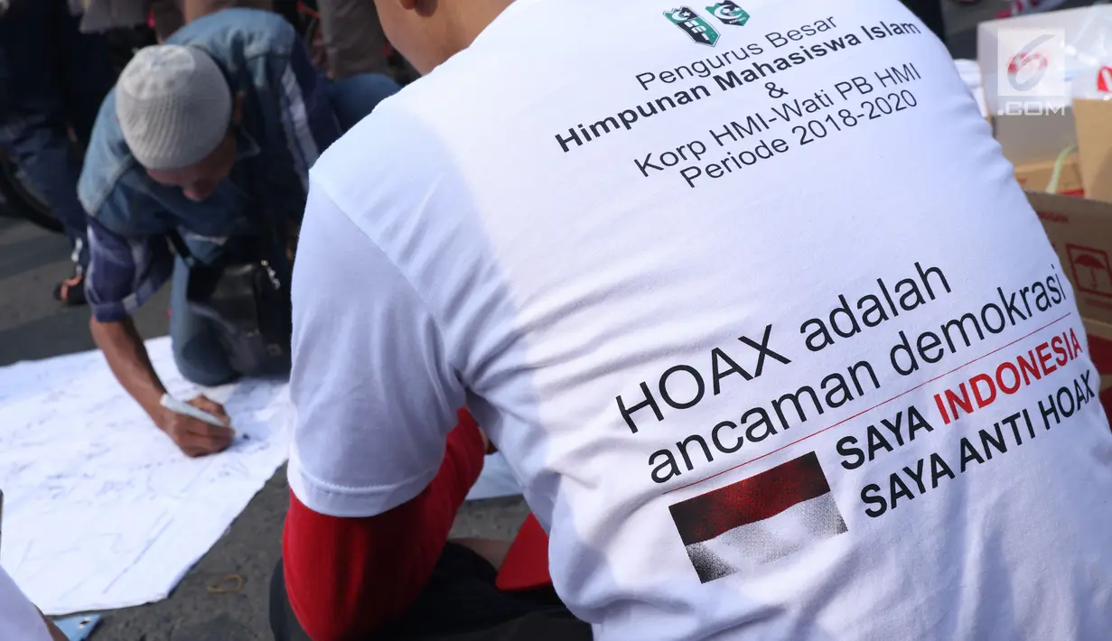 Salah satu pengurus PB HMI melihat warga yang menandatangani spanduk dukungan anti hoax di kawasan Bundaran Hotel Indonesia, Jakarta, Minggu (18/11). PB HMI mensosialisasikan Hoax sebagai ancaman demokrasi di Indonesia. (Liputan6.com/Helmi Fithriansyah)