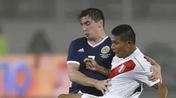 Aksi pemain Peru, Edison Flores (kanan) melepaskan tembakan saat diadang pmeian Skotlandia, Kenny McLean pada laga uji coba di Lima, Peru, (29/5/2018). Peru menang 2-0. (AP/Martin Mejia)