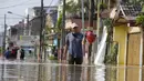 Seorang pria berjalan melalui jalan yang banjir di Bekasi, Jawa Barat, Kamis (17/2/2022). Hujan deras yang dikombinasikan dengan perencanaan pembuangan limbah kota yang buruk sering menyebabkan banjir besar. (AP Photo/Achmad Ibrahim)