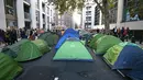 Aktivis iklim mendirikan tenda saat berkemah di jalan utama Westminster, London, Inggris, Selasa (8/10/2019). Aksi yang bertujuan mendesak pemerintah mengekang emisi karbon tersebut bagian dari gerakan Pemberontakan Kepunahan. (Jonathan Brady/PA via AP)