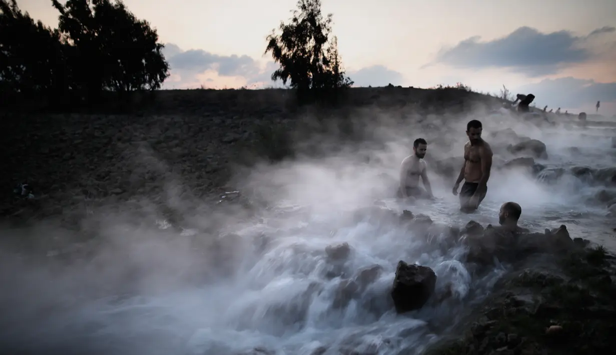 Wisatawan berendam di kolam air panas di utara Dataran Tinggi Golan yang diduduki Israel, 4 November 2017. Air mengalir dari aliran pipa pengeboran di Lembah Hula yang merupakan upaya mengurangi kekeringan di kawasan pertanian. (ENAHEM KAHANA/AFP)