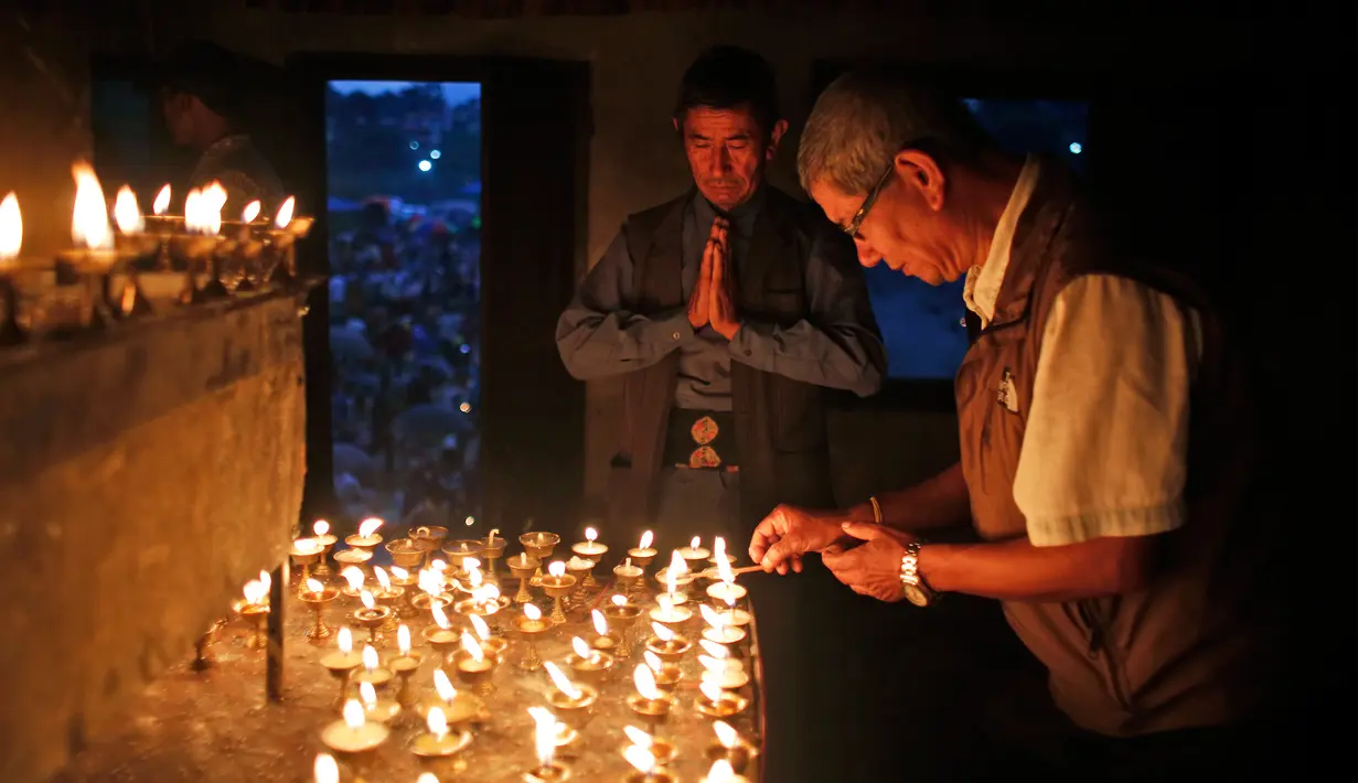 Seorang pria setengah baya menyalakan lampu minyak pada festival Kuse Aunsi di kuil Hindu Gokarneshwar di Kathmandu, Nepal (21/8). Kuse Aunsi lebih dikenal dengan sebutan Gokarna Aunsi. (Niranjan Shrestha/AP)