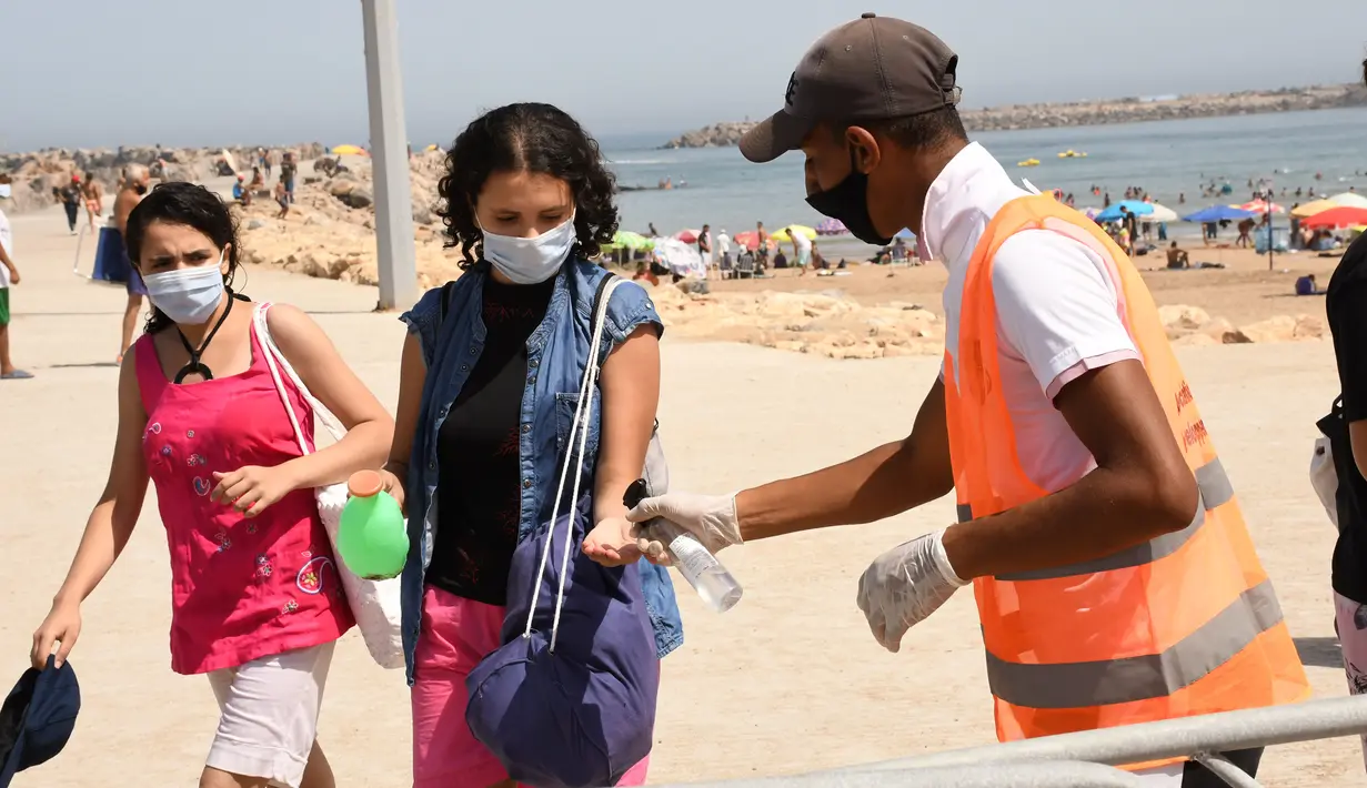 Petugas kesehatan membantu seorang wanita membersihkan tangannya di sebuah pantai di Rabat, Maroko, 27 Agustus 2020. Maroko pada 27 Agustus 2020 melaporkan 1.221 kasus baru COVID-19, menambah jumlah kasus infeksi di negara itu sejak 2 Maret menjadi 57.085. (Xinhua/Chadi)