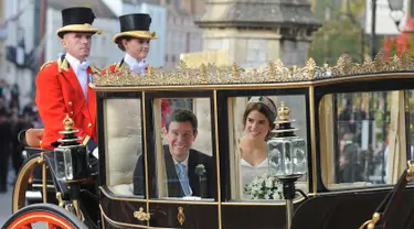 Putri Eugenie dan Jack Brooksbank menaiki kereta kencana usai melangsungkan pernikahan di Kapel St. George, Windsor Castle, London, Inggris,  Jumat (12/10). Putri Eugenie merupakan anak bungsu Pangeran Andrew dan Sarah Ferguson. (AP Photo/Rui Vieira)