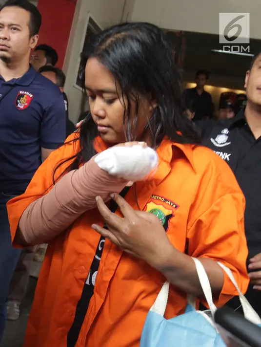 Istri tersangka pembunuhan wartawan Abdullah Fitri Setiawan alias Dufi yang tewas dalam drum, Sari menutupi wajahnya saat digelandang petugas di Polda Metro Jaya, Jakarta, Rabu (21/11). (Merdeka.com/Imam Buhori)