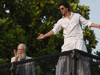 Aktor Bollywood, Shah Rukh Khan (kanan) disaksikan pembawa acara televisi AS, David Letterman menyapa para fans yang berkumpul di depan rumahnya pada perayaan Idul Fitri di Mumbai, Rabu (5/6/2019). Shah Rukh Khan tetap melakukan tradisi menyapa penggemar dari balkon atas rumahnya (SUJIT JAISWAL/AFP)